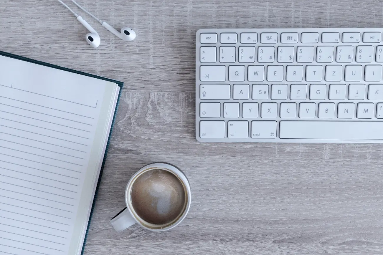 Un bureau vu de dessus : clavier, carnet et tasse