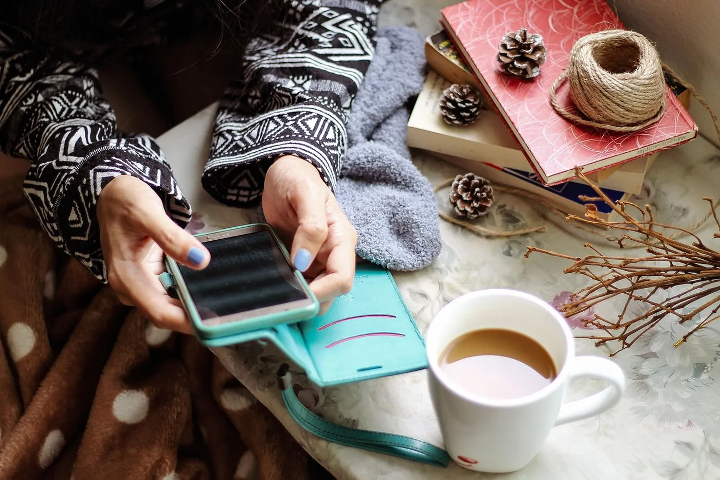 Une personne consulte une application sur son smartphone, une tasse à la main