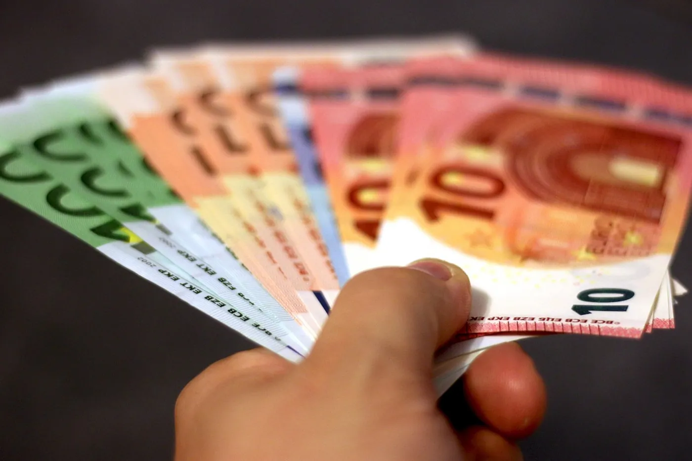 Une main tient des billets en euros